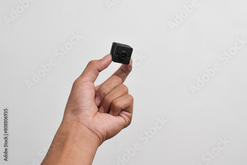 Fotografie Hand holding a spy camera isolated on white background