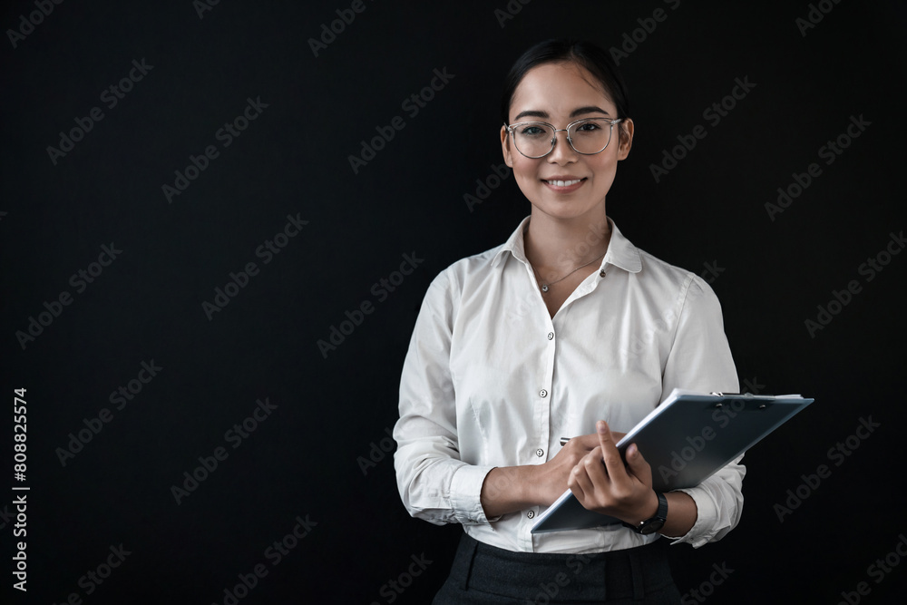 Smiling young businesswoman manager student teacher in eyeglasses wearing formal wear suit standing against background holding folder with documents, clipboard. Smiling young businesswoman manager student teacher in eyeglasses wearing formal wear suit standing against background holding folder with documents, clipboard.