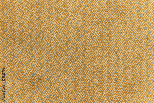 abstract background of an old yellow carpet with interesting diamond pattern close up