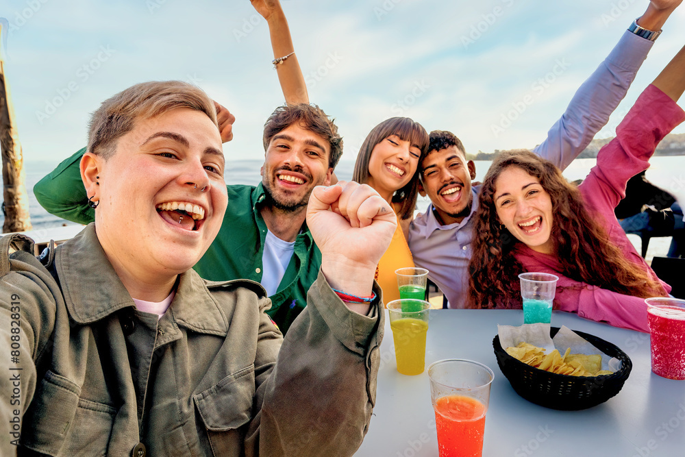 Φωτογραφία Group of diverse friends selfie - laughing and enjoying drinks at a beach gathering, showing joy and togetherness in a casual outdoor setting