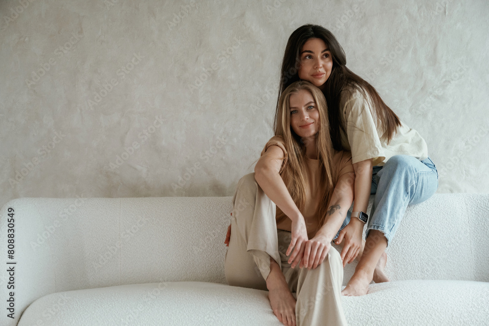 Against white wall. Two happy young female best friends are indoors Against white wall. Two happy young female best friends are indoors