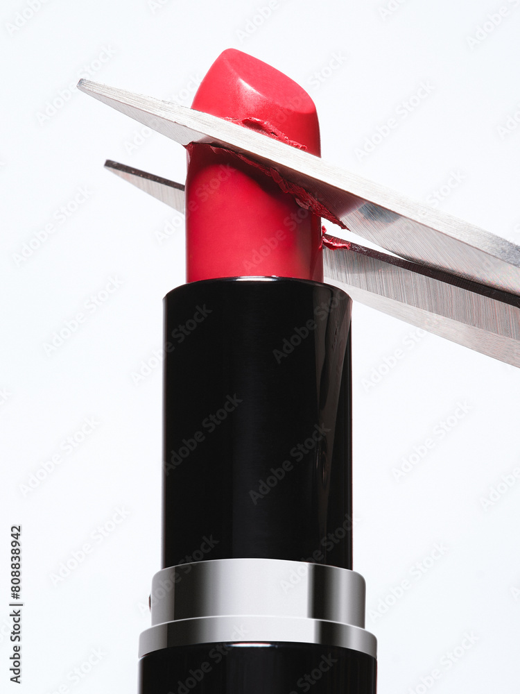 Fotografie Luxury red lipstick being cut by scissors