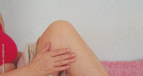 Woman sits and massages her knee with both hands.