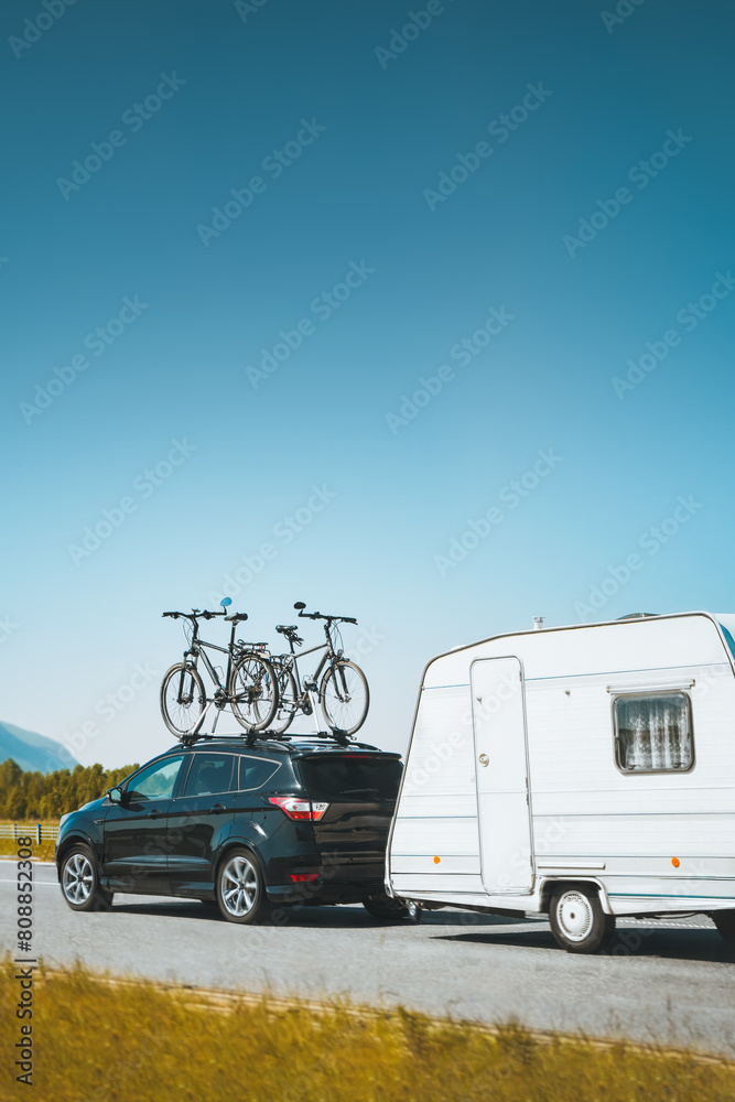SUV car truck with bicycles on the roof and towing RV. Family road trip
