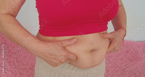 Close up of woman hands holding her belly fat.
