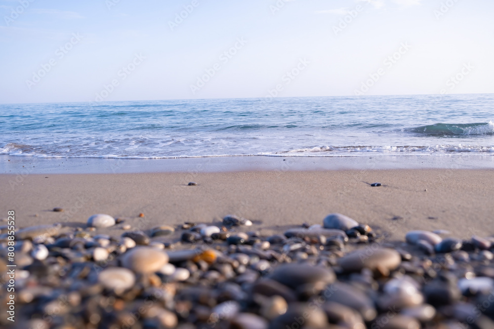 Warm sunrise illuminating a pebble-covered beach with gentle waves, casting a serene glow on the shoreline. Warm sunrise illuminating a pebble-covered beach with gentle waves, casting a serene glow on the shoreline.