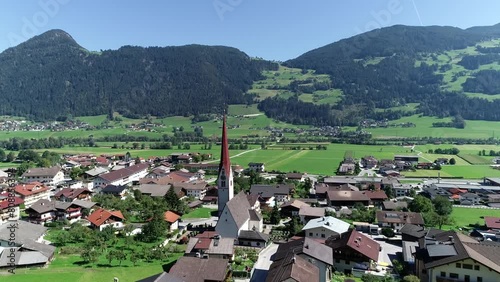 Aerial view moving towards Pfarrkirche located in Schlitters a small town in Zillertal valley in Austria near the strongly glaciated section of the Alps also most visited by tourists in the area 4k photo