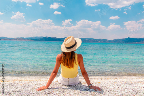 Woman admiring the magnificent view of Salda Lake. The woman sits against the view and poses with her hat. Salda Lake, Burdur, Turkey. photo