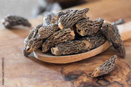 Dry Morel Mushrooms on Wooden Platter. Close-up of textured morel mushrooms, artfully arranged on a rustic wooden platter, emphasizing their unique structure.