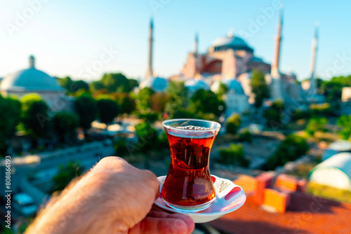 The Hagia Sophia Mosque. Man drinks black Turkish tea in front of the view. In the photo, the tea is clearly captured, while Hagia Sophia is blurred. Istanbul Turkey.. photo