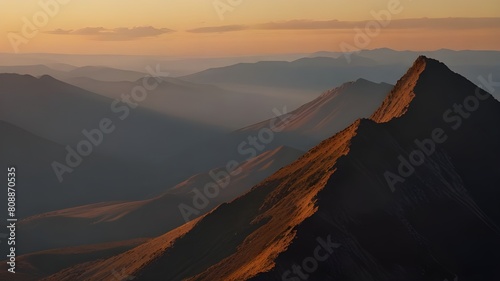 A rugged mountain range bathed in the warm hues of sunrise  casting long shadows across the valley below.