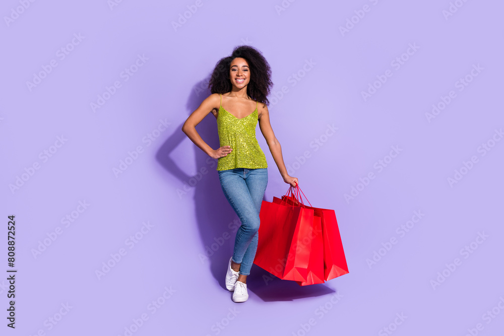 Full length photo of gorgeous young girl posing hold shopping bags wear trendy green sequins outfit isolated on purple color background Full length photo of gorgeous young girl posing hold shopping bags wear trendy green sequins outfit isolated on purple color background