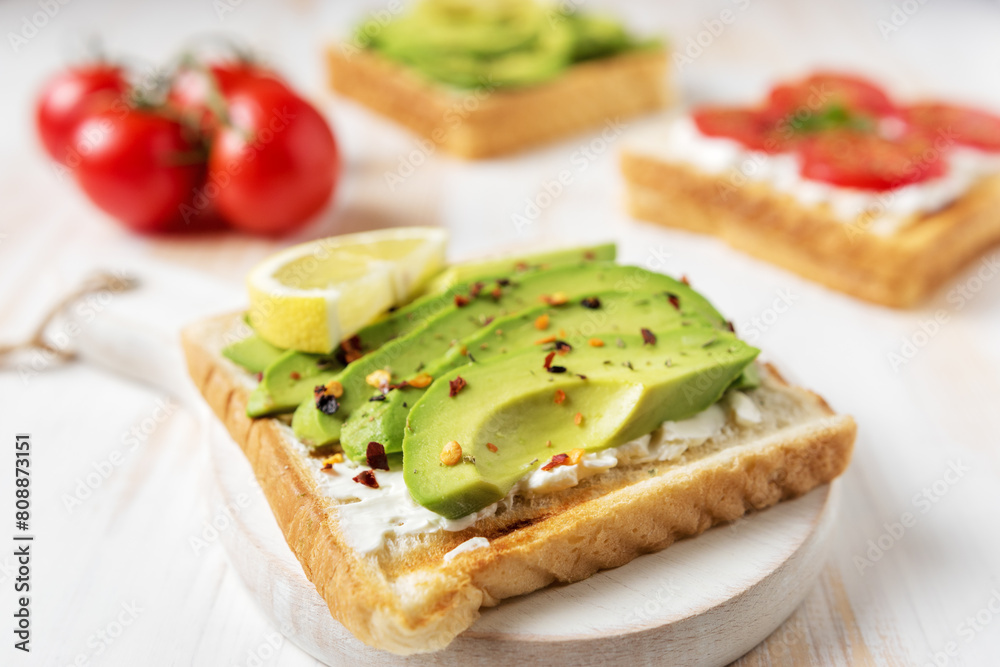 Sliced avocado on toast bread with spices on white wooden background. Food concept. Sliced avocado on toast bread with spices on white wooden background. Food concept.