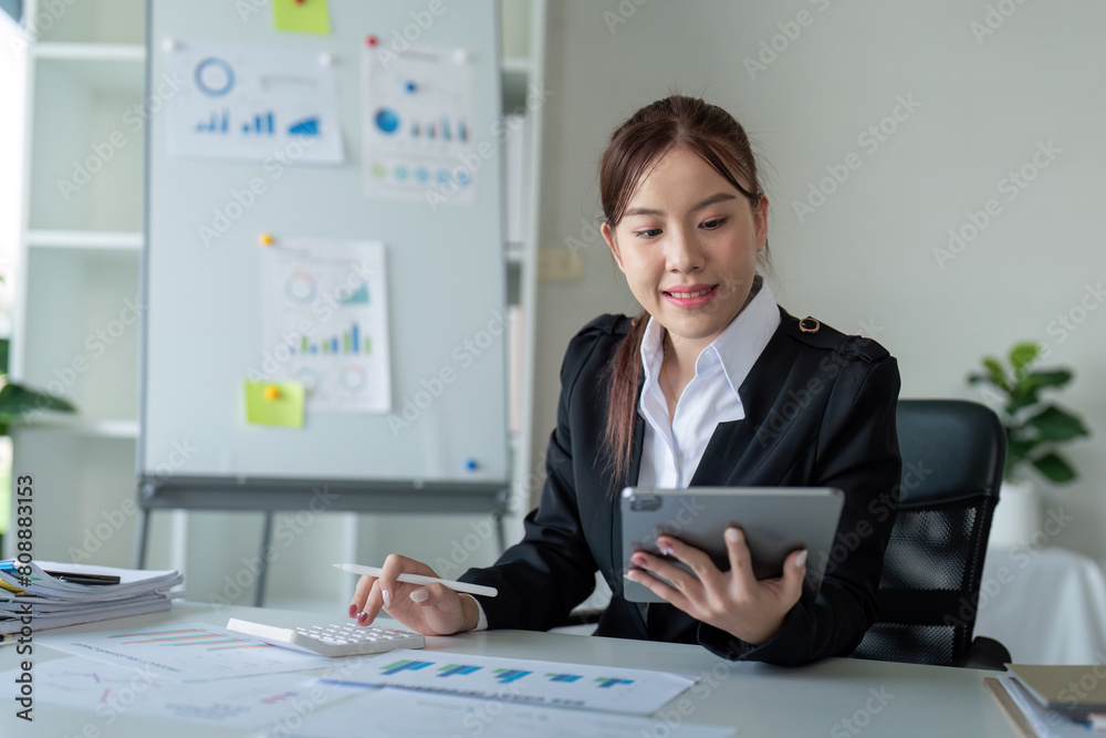 Fototapeta premium Businesswoman in office using tablet computer, audit documents and financial analysis, business people concept