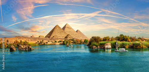 Lonely Saleboat in the Nile river and ancient rocks in the Aswan desert by the pyramids, Egypt