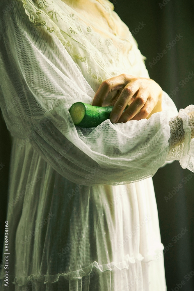Φωτογραφία woman in white romantic style dress holding a zucchini in her arms