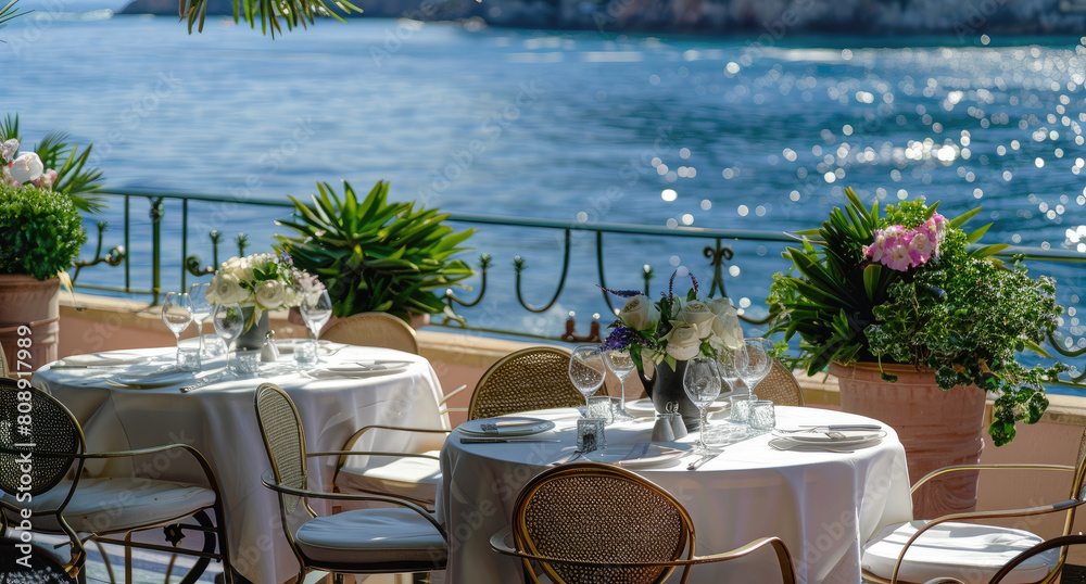 Dining tables were set up on the terrace of an elegant restaurant with a sea view in Monaco, overlooking lush greenery and blue waters