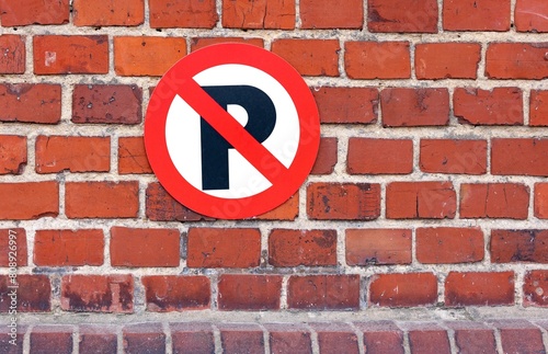 Red traffic sign with forbidden parking on red brick wall