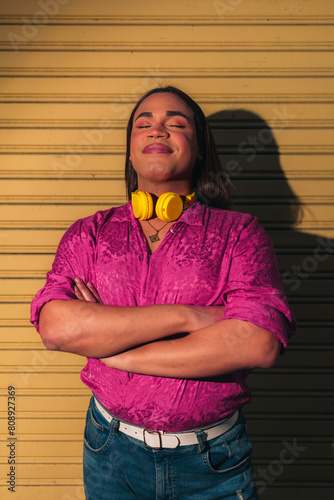 Confident and inspirational LGBT woman with crossed arms against yellow background. LGBT concept.