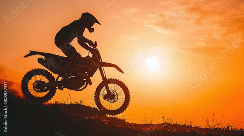 Motorcyclist Riding Dirt Bike on Hill at Sunset Orange Sky Silhouette Action Shot