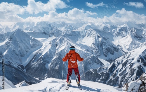 An avid skier stands at the summit, overlooking the expanse of the alpine range, as the clear sky reflects in the visor of his helmet, signaling readiness for the descent.