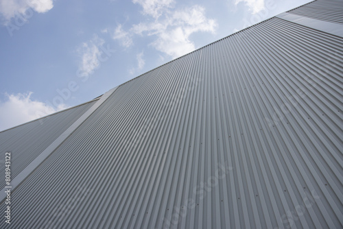 A large factory building with a grey roof and a blue sky in the background