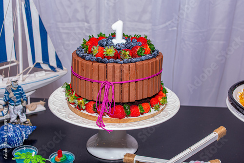 bolo de aniversário de chocolate, morango e mirtilo em um prato branco de porcelana
