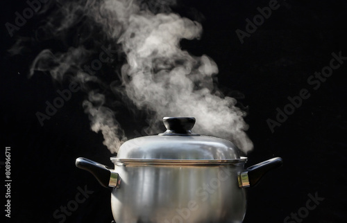 steam over cooking pot in kitchen on dark background