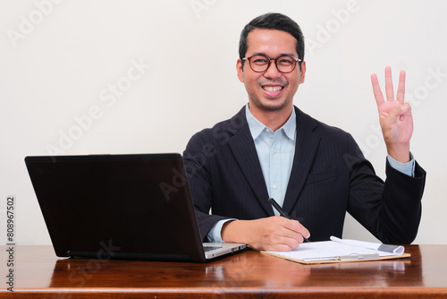 A recruiter staff smiling at the camera and give three fingers sign while sitting