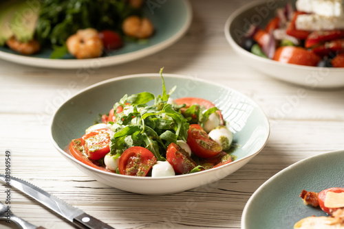 Italian caprese salad in restaurant. Fresh mozzarella, cherry tomatoes and basil leaf with pesto sauce. Organic and healthy food