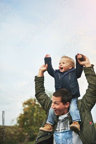 Family, shoulder and father with baby in park for bonding, playing and laugh together outdoors. Nature, blue sky and happy dad carry young boy for child development, love or fun on weekend or holiday
