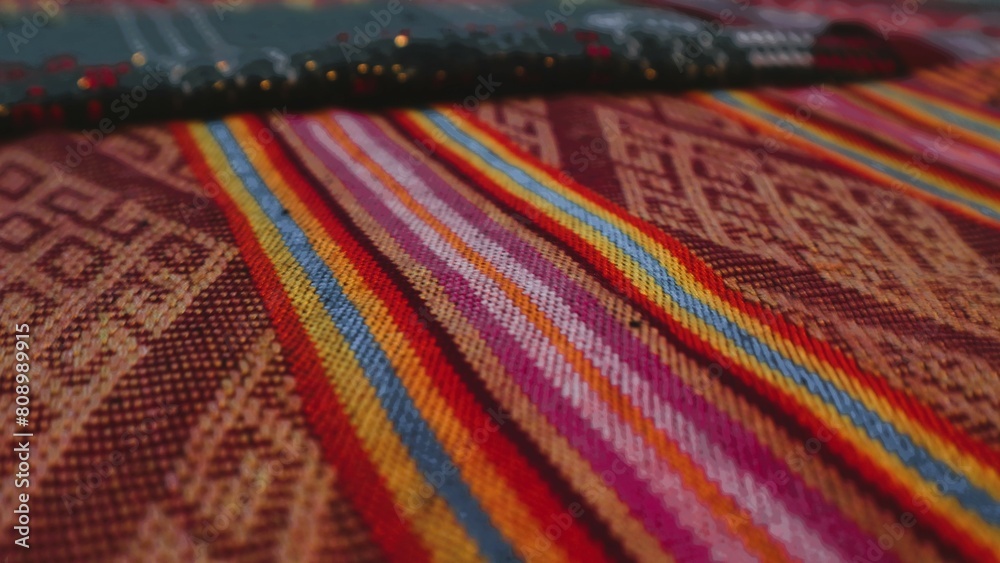 Close up side view handmade woven fabric with unique pattern from Indonesia, selective focus, multicolour textured textile background Close up side view handmade woven fabric with unique pattern from Indonesia, selective focus, multicolour textured textile background