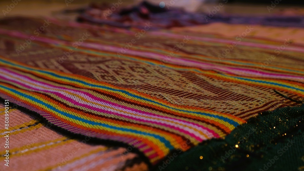 Close up side view handmade woven fabric with unique pattern from Indonesia, selective focus, multicolour textured textile background Close up side view handmade woven fabric with unique pattern from Indonesia, selective focus, multicolour textured textile background