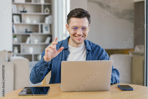 A joyful young professional engagingly communicates during a video call in a modern and stylish living area, expressing satisfaction and confidence. photo