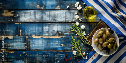 Greek food and flag on a blue background. Typical mediterranean dishes in Greece. Olive, olive oil, feta cheese, salad, fresh vegetables, herbs. Food menu, copy space design.