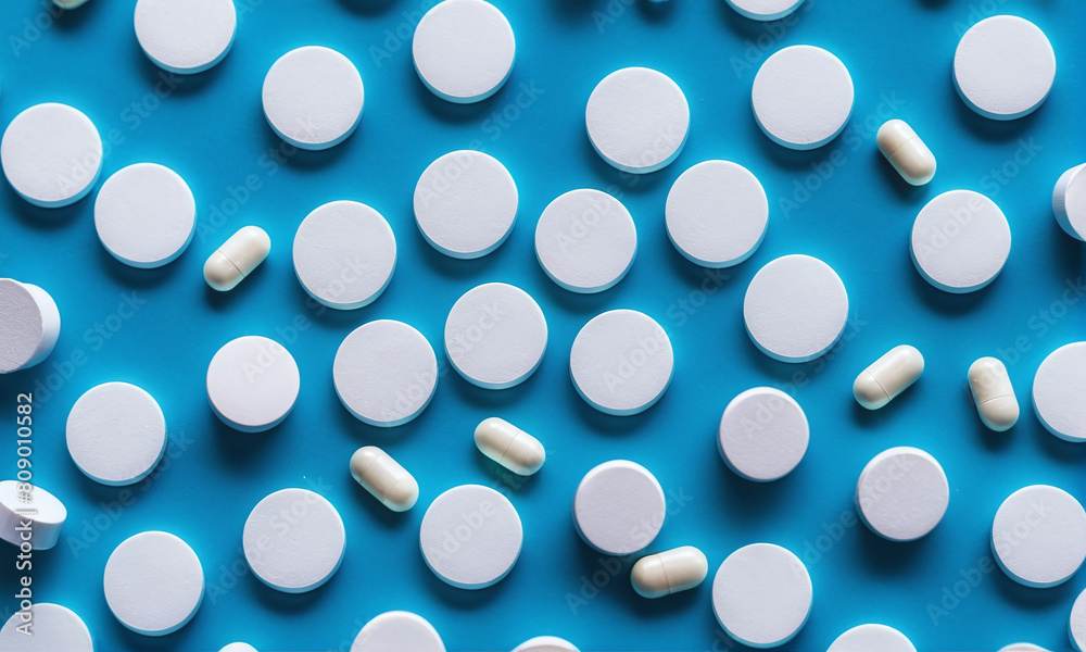 A large number of pills are on the table, blue background
