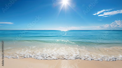 A beautiful beach with a clear blue ocean and a few small islands in the distance. The sky is mostly clear with a few clouds scattered throughout. The scene is peaceful and serene  with the calm ocean