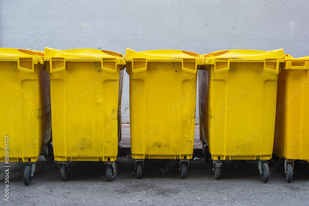 several yellow containers for recycling packaging on a street several yellow containers for recycling packaging on a street