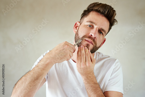 Man, portrait and scissors in home bathroom for grooming, skincare or morning routine for wellness. Face, trim beard or serious person cleaning for beauty, health or hair removal for hygiene in house