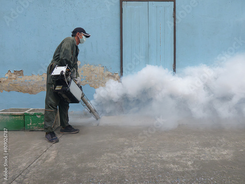 A man sprays chemical fog to kill Aedes mosquitoes. Causes of dengue fever