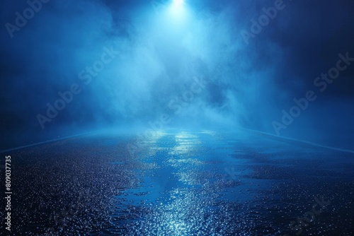 The foggy street with wet asphalt and searchlight illumination creates a mysterious atmosphere against a dark blue backdrop.