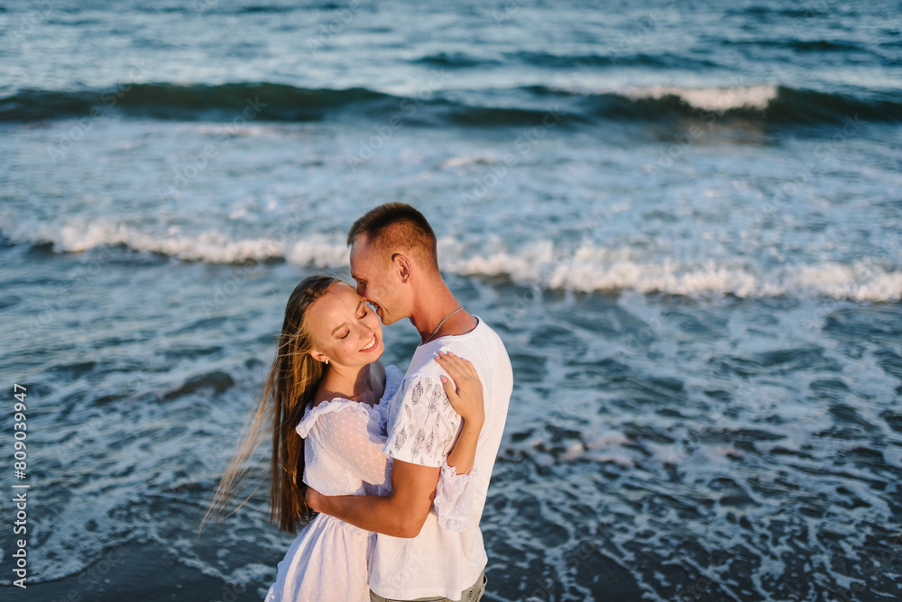 Man embraces woman walk on sand sea. Female kiss and hugs male stand on beach ocean and enjoy sunny summer day. Couple in love hugging and kissing on seashore. Spend time together. Top view Man embraces woman walk on sand sea. Female kiss and hugs male stand on beach ocean and enjoy sunny summer day. Couple in love hugging and kissing on seashore. Spend time together. Top view