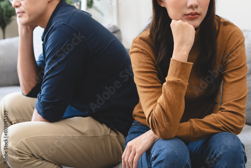 Family problem concept, Close-up hands of Asian wife sitting on sofa and husband sitting back to back in the living room at home have problems in a relationship and have an argument photo