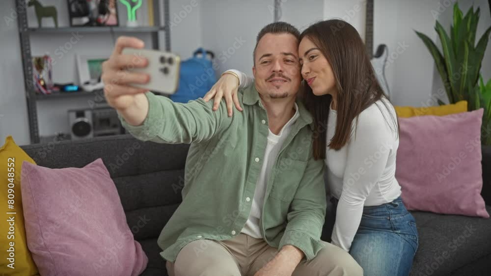 A couple in a cozy living room takes a selfie, capturing their affectionate moment, featuring a woman, a man, and a modern interior. A couple in a cozy living room takes a selfie, capturing their affectionate moment, featuring a woman, a man, and a modern interior.