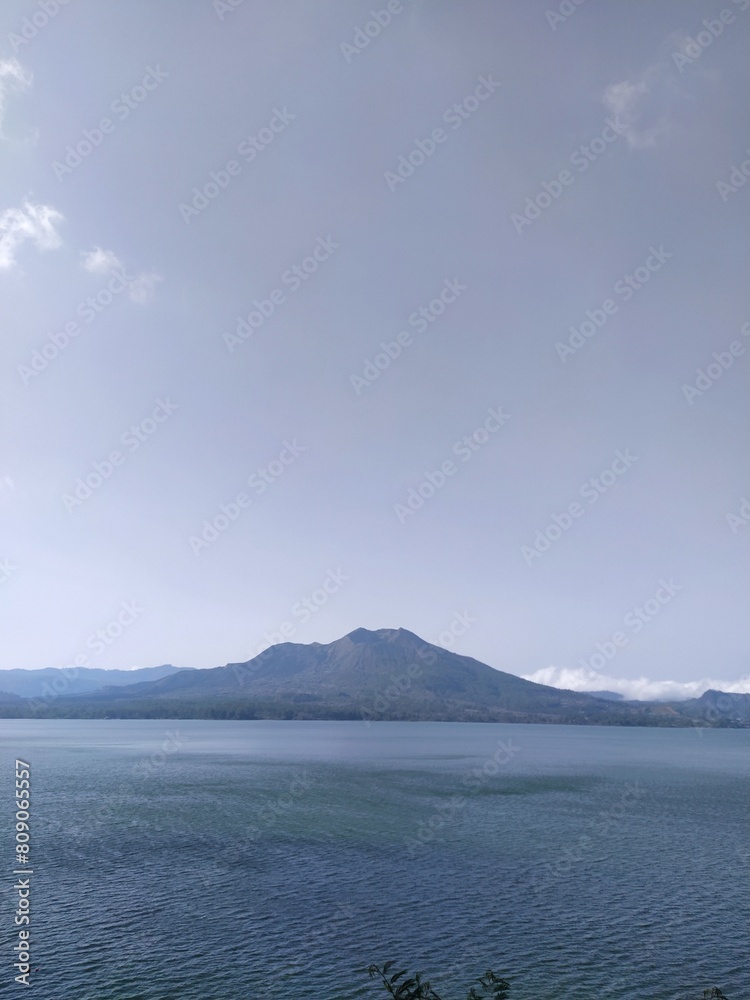 Lake Batur, a crater lake in Kintamani, Bali, Bangli Regency, against the backdrop of a mountain. Sunny day, blue sky