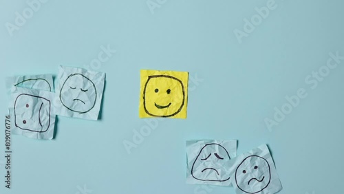 Sad faces on blue stickers and one yellow happy one. Positive sticker, smile sign on background of sad symbols. Concept of success and winning in business.