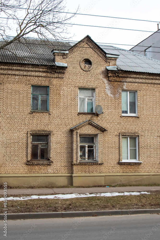 Obraz premium Brick building with tree in front, showcasing classic facade and wooden fixture