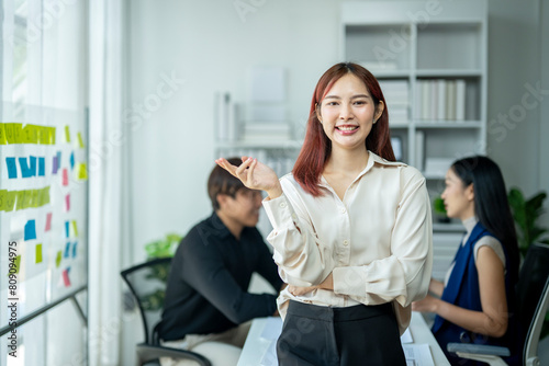 A woman in a white shirt stands in front of a white board with a smile on her fa