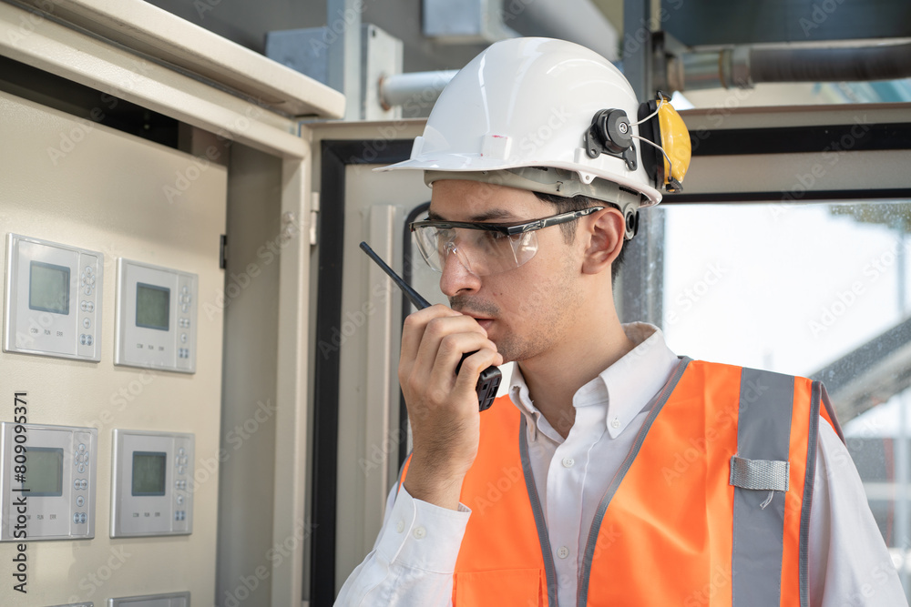 Portrait Asia male engineer in protective workwear is checking a electrical control cabinet or circuit electric control button with at rooftop building Portrait Asia male engineer in protective workwear is checking a electrical control cabinet or circuit electric control button with at rooftop building