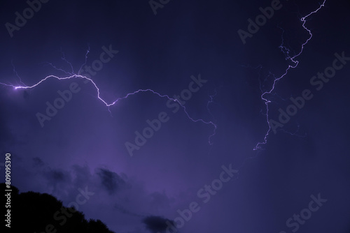 inquadratura dettagliata di vari fulmini che colorano il cielo di viola durante un intenso temporale notturno, in estate photo